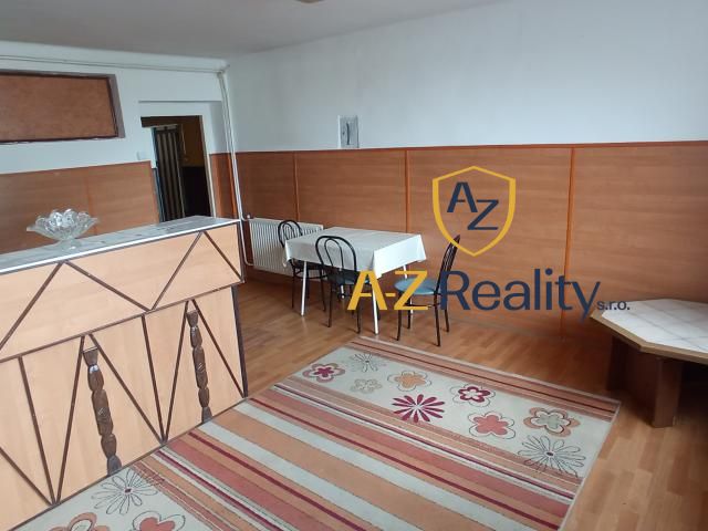 The interior of a building with a wooden decor floor, table, chairs, and a carpet.