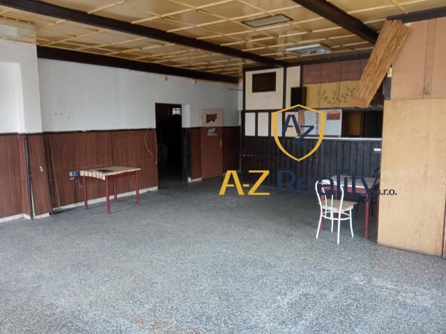 The building has old tables, a chair, wall paneling, and a stone floor.