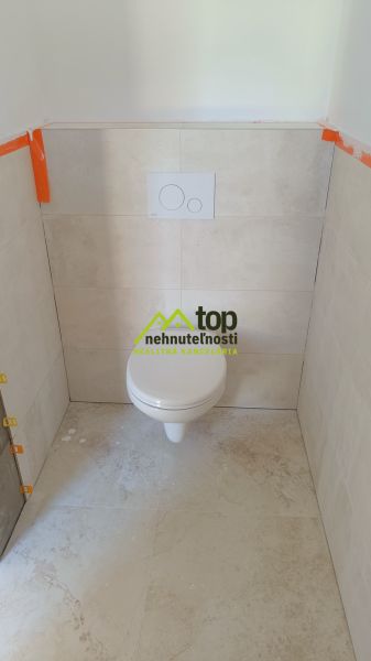 A toilet in a family house with ceramic tiles and a floor with a stoneware design.