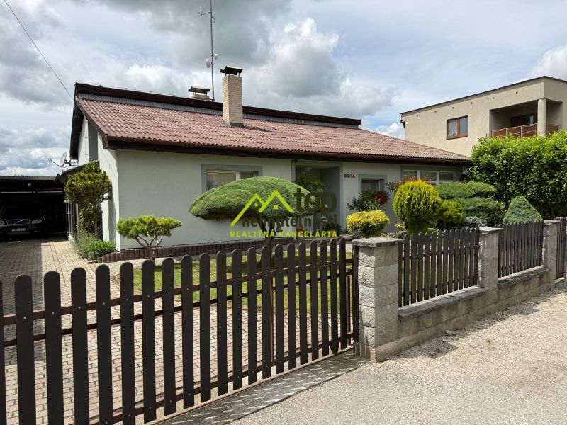 A family house in Chrabrany with a landscaped garden, fence, and driveway.