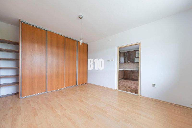 A room with a wooden decor floor and a built-in wardrobe in a 2-room apartment.
