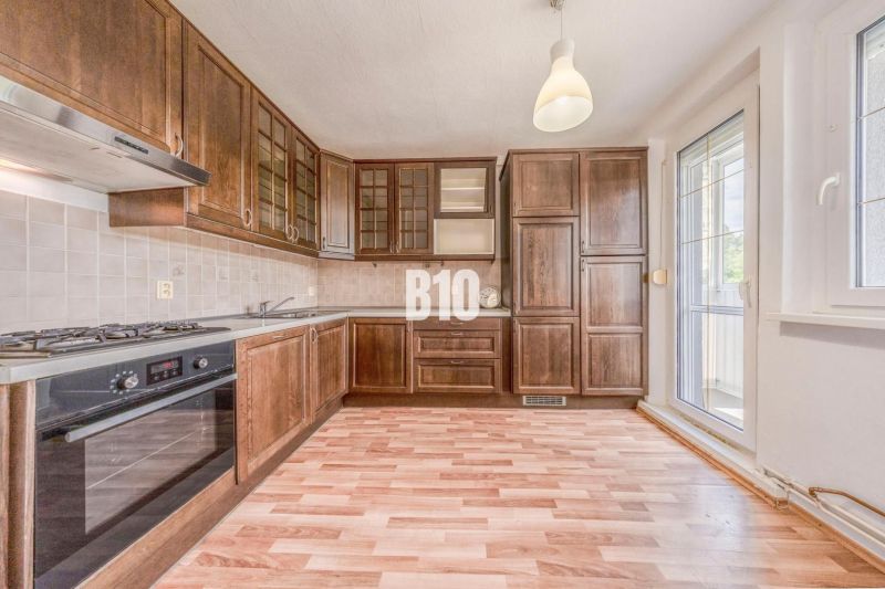 A kitchen in a 2-room apartment with a wooden decor and balcony doors.