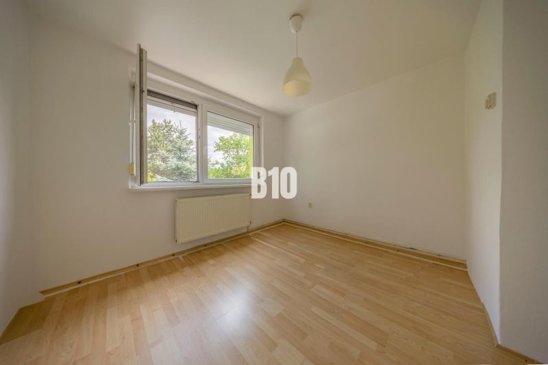 A room with a wooden floor decor and an open window in a 2-room apartment.