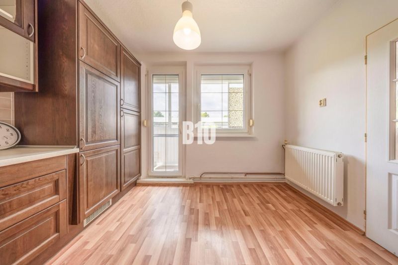 A kitchen space with wooden cabinets and a wood-patterned floor in a 2-room apartment.