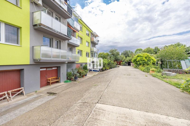 An apartment building on Družstevná Street in Malinovo with a road surrounded by greenery.