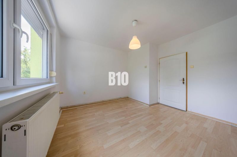 A room in a 2-room apartment with white walls and a wooden decor floor.