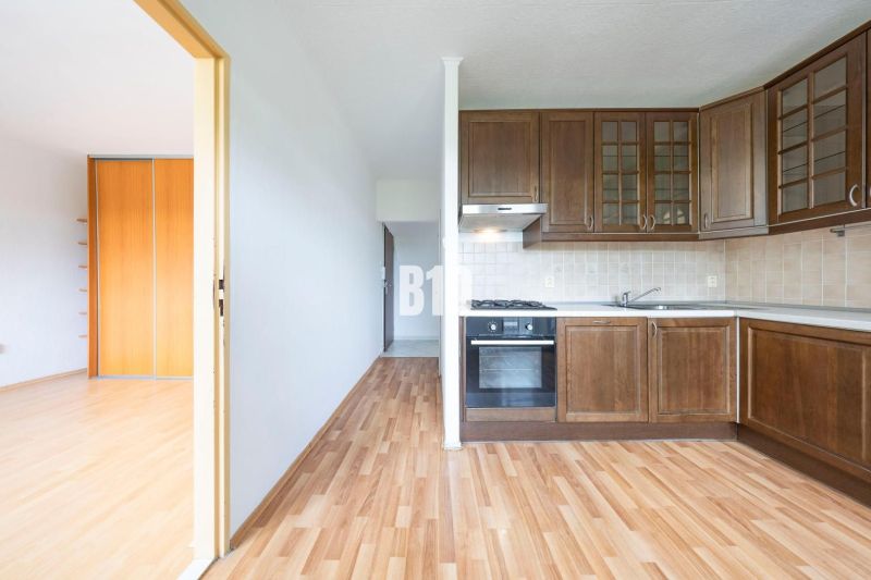 A kitchen with wooden cabinets and a floor with a wooden decor in a 2-room apartment.