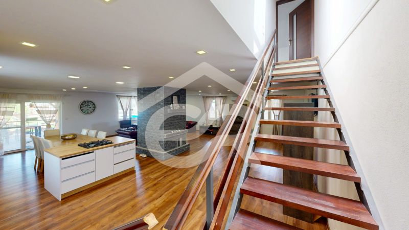 Interior of a family house with an open kitchen, wood-patterned flooring, and a staircase.