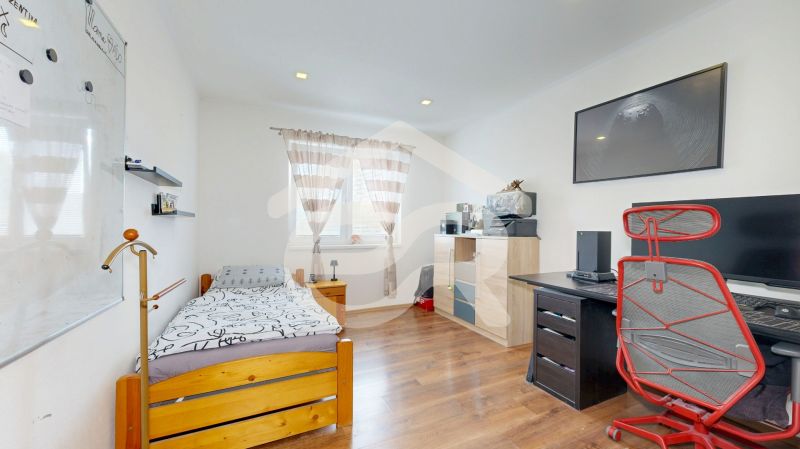A room in a family house with a bed, a desk, and a floor with a wooden decor.