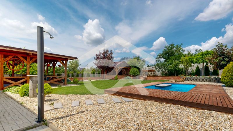 A garden of a family house in Lehota with a gazebo, a swimming pool, and a manicured lawn.