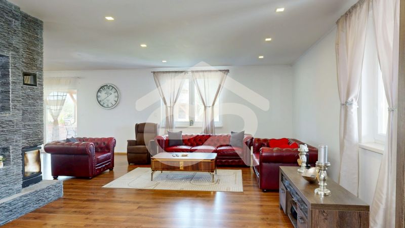 Living room in a family house with a fireplace, sofa set, and wooden decor flooring.