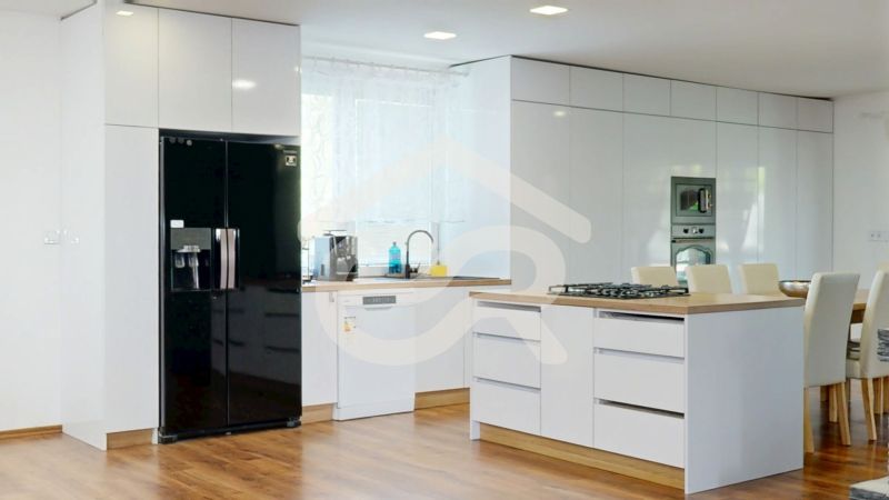 A kitchen in a family house with white cabinets and a wooden decor floor.