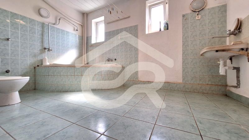 A bathroom in a family house with a tiled bathtub, toilet, and sink.