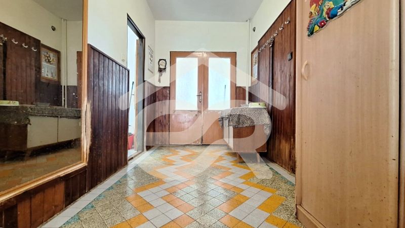 A hallway in a family house with colorful tiles and wooden wall paneling.