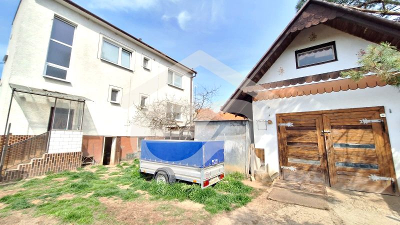 A family house on Štúrova Street in Ludanice with wooden garage doors and a trailer.