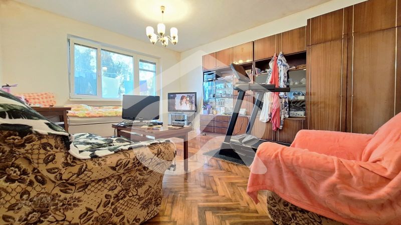 Living room in a family house with sofas, TV, and wooden decor flooring.