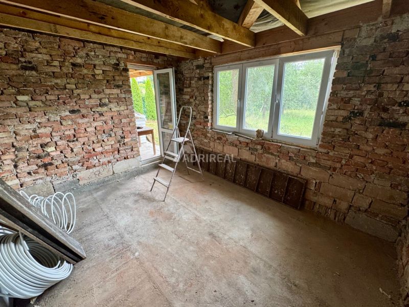 A room in a family house with brick walls and a large window.