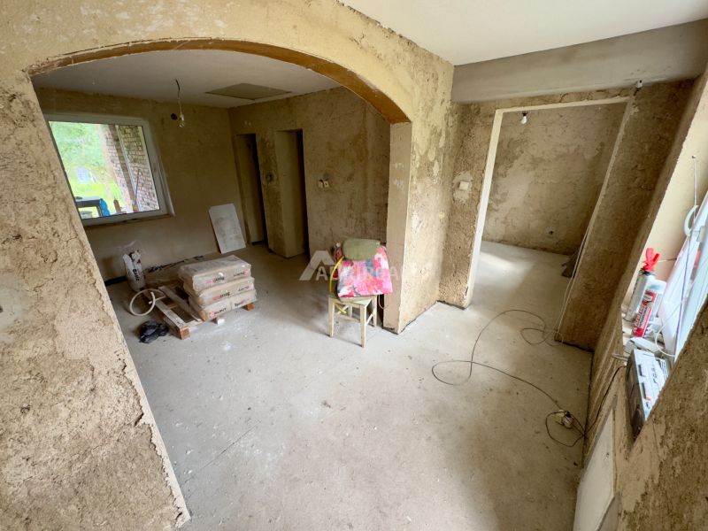 Interior of a family house with raw walls, construction materials, and a cardboard floor.