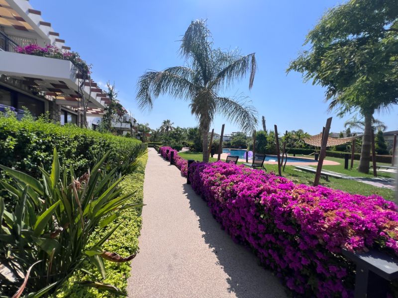 A resort in Agia Eirini with a pool and a flower-lined walkway.