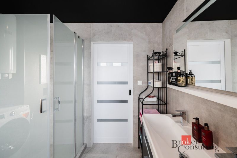 Bathroom in a 2-room apartment with a sink, shower, and a shelf for accessories.