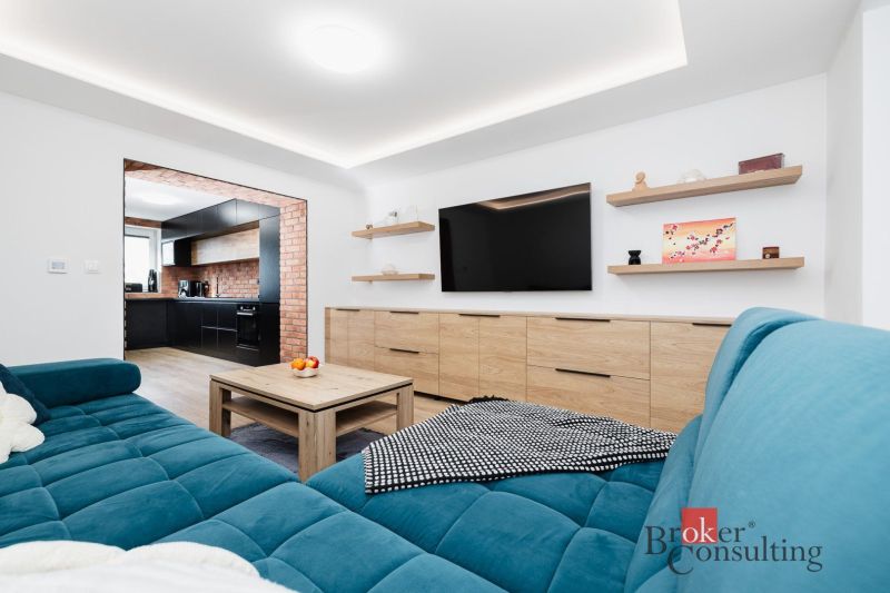 Living room with wood-patterned flooring and a blue sofa in a two-room apartment.
