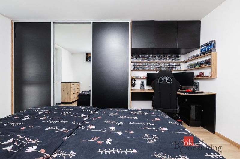 Bedroom in a 2-room apartment with a wardrobe, desk, and floor with wood decor.