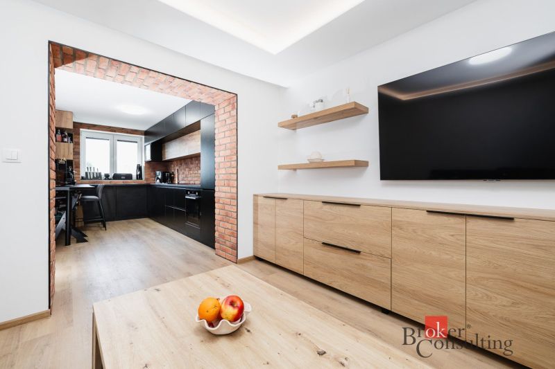 A kitchen in a 2-room apartment with brick details and a wooden decor floor.