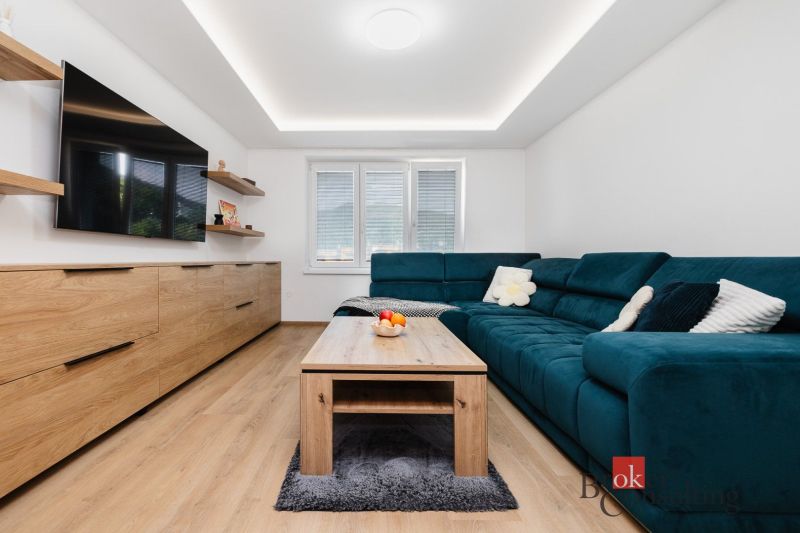 Living room in a two-room apartment with a blue sofa and a wooden decor floor.