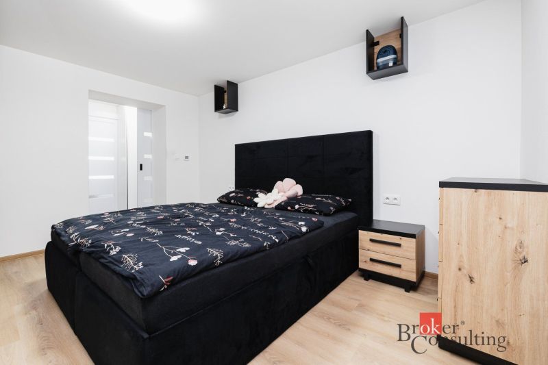 A bedroom in a two-room apartment with a black bed and a wooden decor floor.