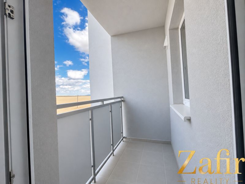 A balcony in a one-room apartment with a view of the sky and a clear blue color.