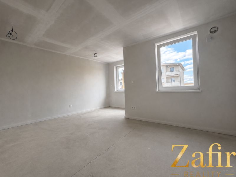 Unfurnished space in a one-room apartment with white walls and concrete floor.