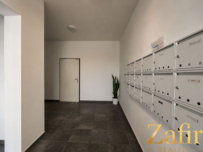 Entrance hall with mailboxes and gray tiles in a studio apartment.