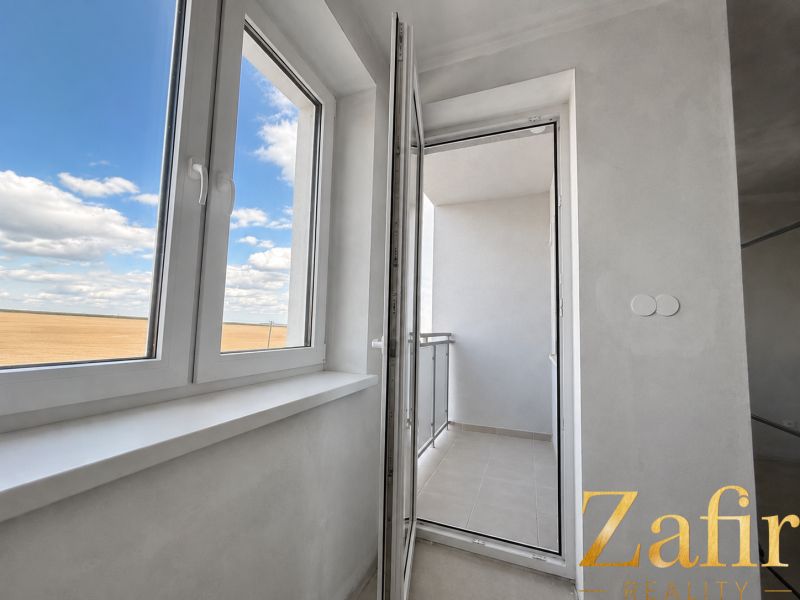 A spacious balcony with a view in a 1-room apartment, white walls and a blue sky.