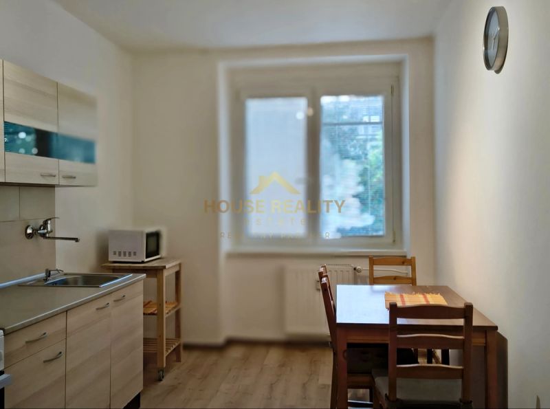 A kitchen in a studio apartment with a dining table and a wooden decor floor.