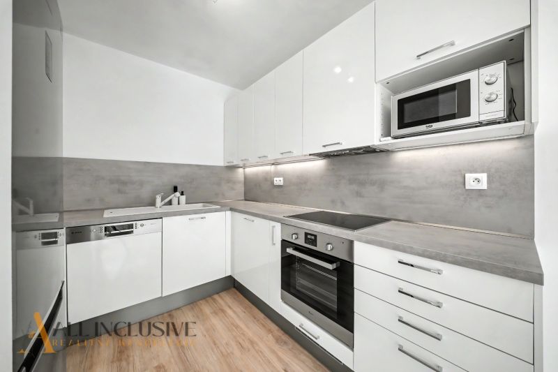 A kitchen with a corner unit and a wooden decor floor in a 2-room apartment.