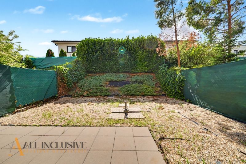 A garden in a 2-room apartment in Dunajská Lužná with tiles and a green fence.