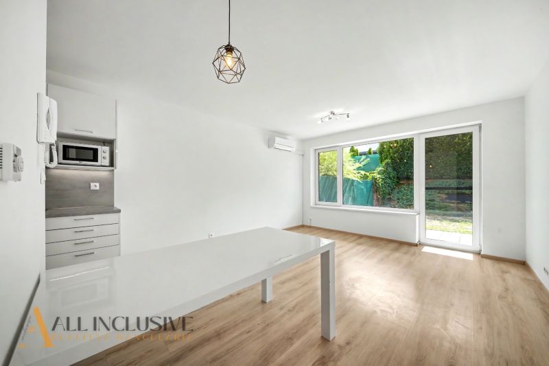 A bright interior of a 2-room apartment with wood-patterned flooring and large windows.