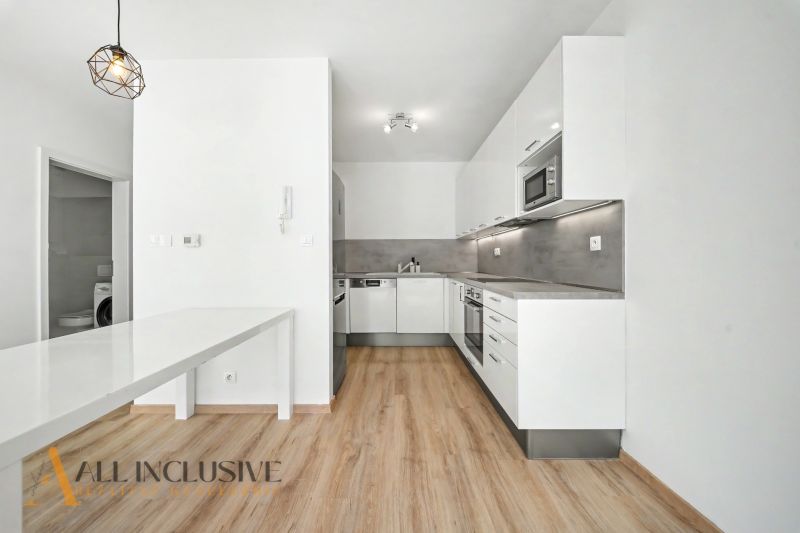 A kitchen in a 2-room apartment with a wooden decor floor and built-in appliances.