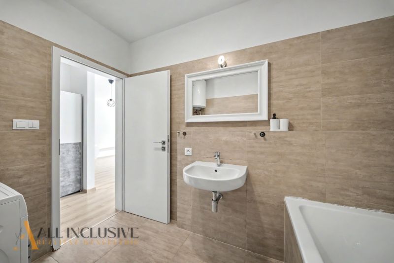 Bathroom in a 2-room apartment with beige tiles and an open door to the hallway.