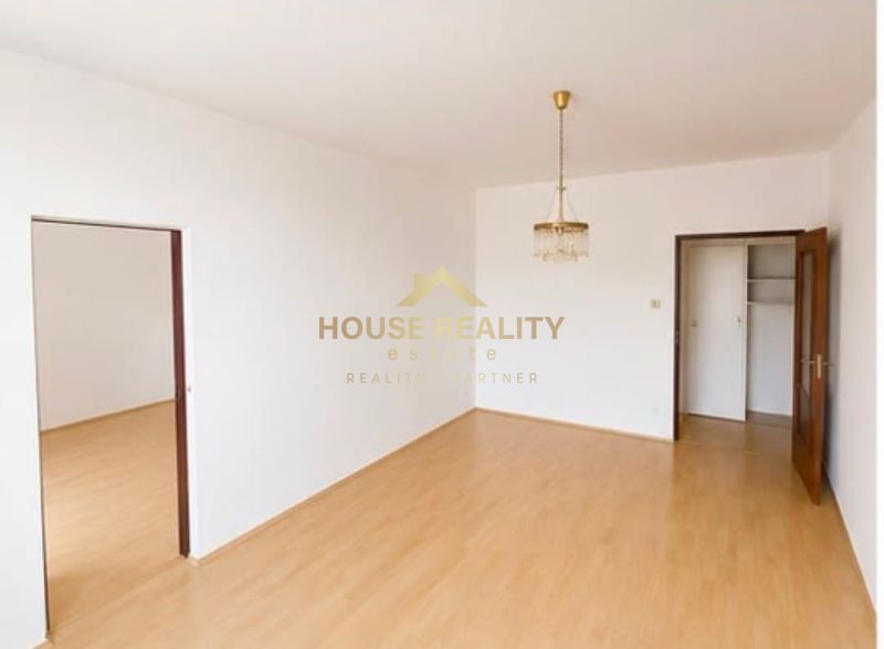 A room in a three-room apartment with a wooden decor floor and a chandelier.