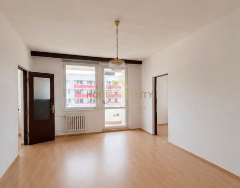 A spacious room with a wooden decor floor and two windows in a 3-room apartment.