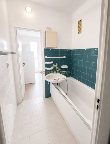 A bathroom with green tiles and a bathtub in a 3-room apartment.