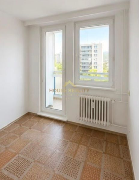 A room in a 3-room apartment with a wooden decor floor and a view of the city.