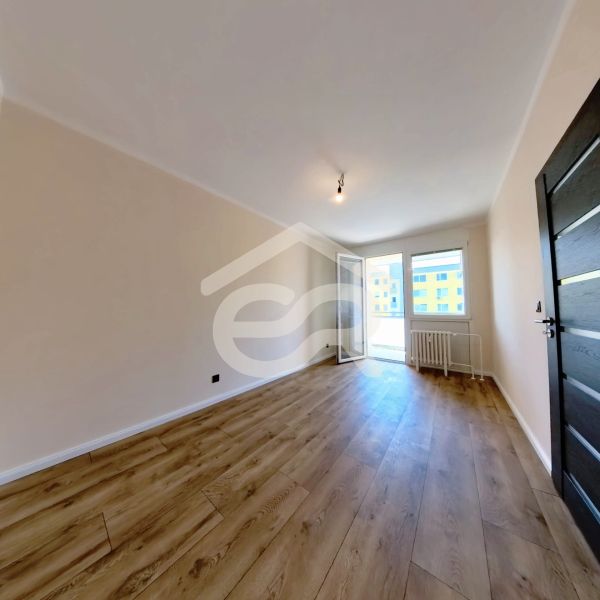 A room in a 3-room apartment with a wooden decor floor and access to a balcony.