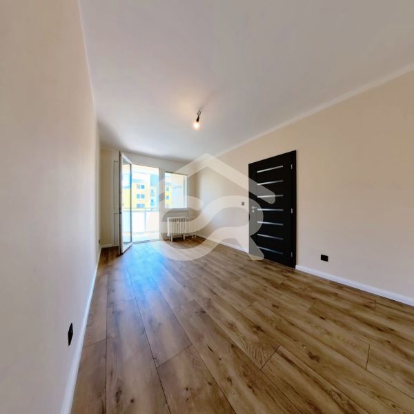 A bright room with wood-patterned flooring in a 3-room apartment.