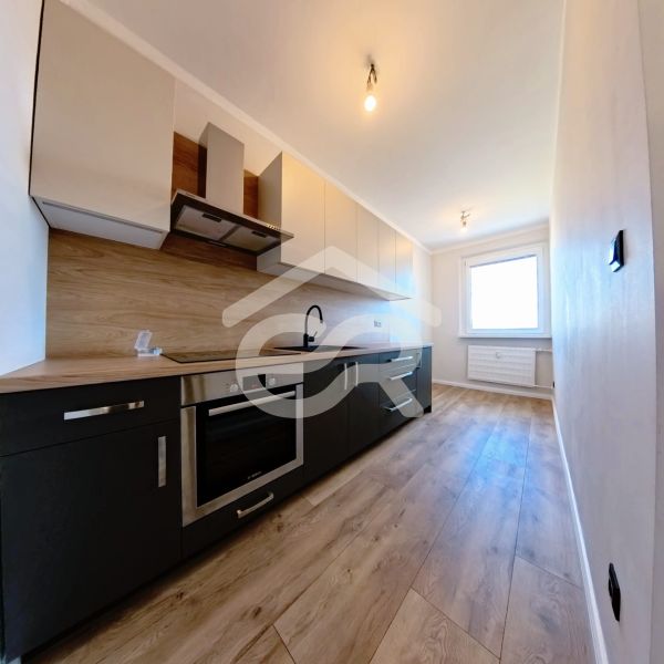 A bright kitchen with wood-patterned flooring in a three-room apartment.