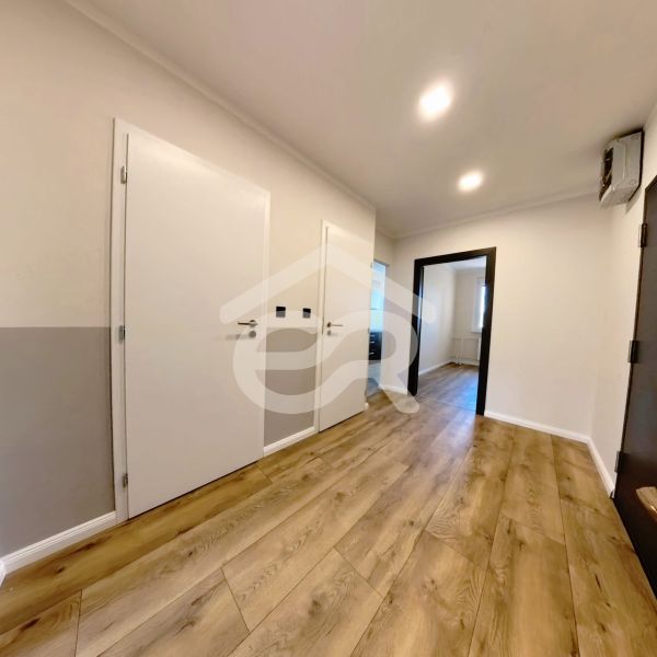 A hallway with a wooden decor floor and white doors in a 3-room apartment.
