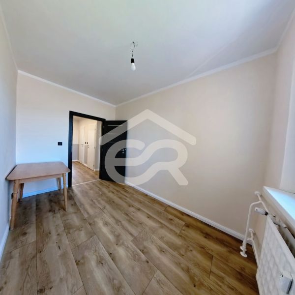 A room in a 3-room apartment with a wooden decor floor and a table.