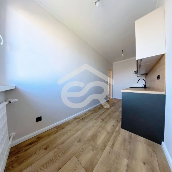 A kitchen in a 3-room apartment with a wooden decor floor and light walls.