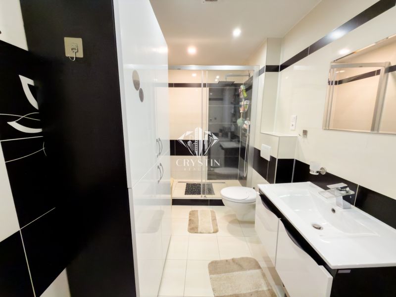The bathroom of a 3-room apartment with a modern shower, white furniture, and tiles.